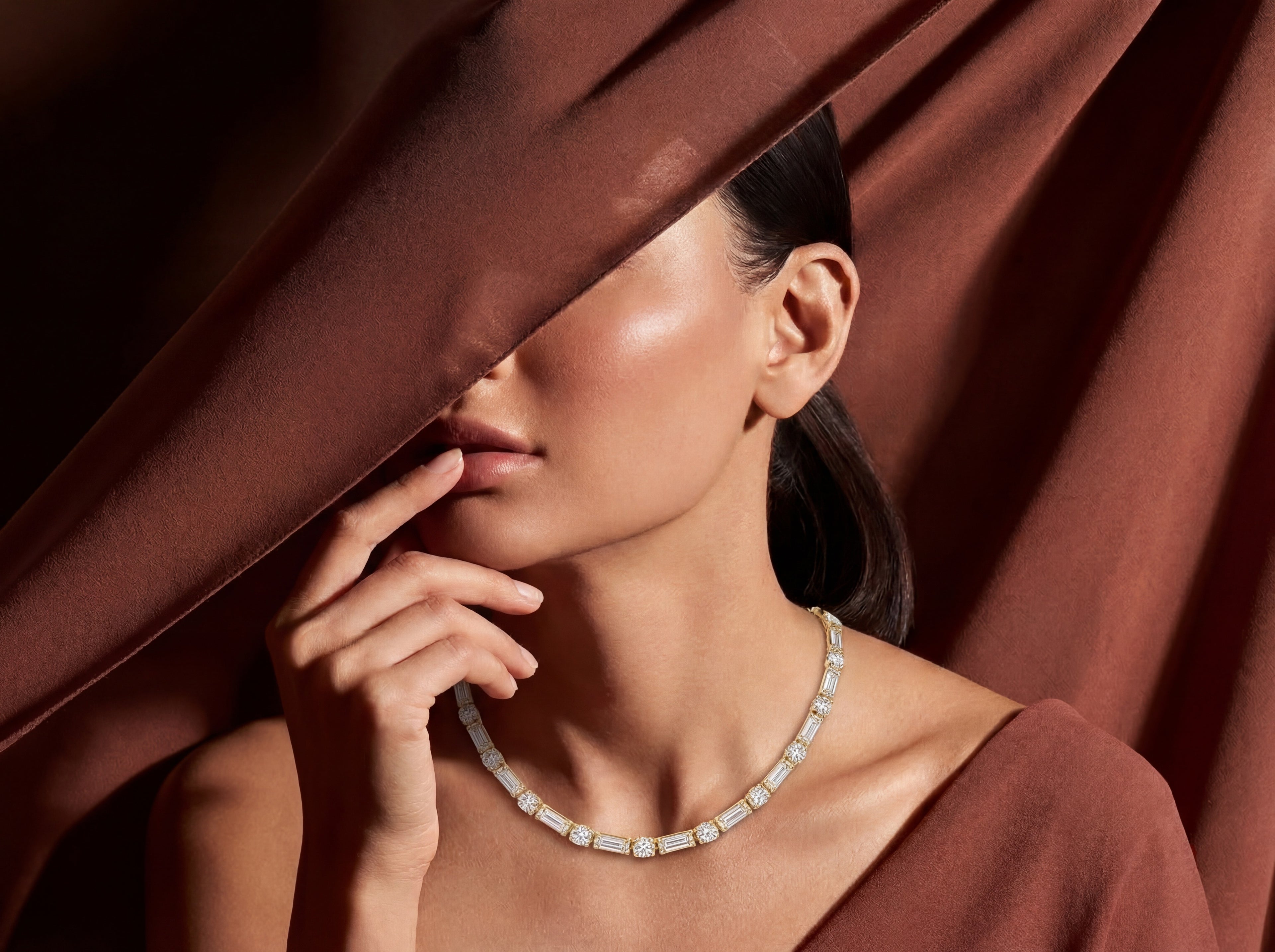 Woman wearing a diamond necklace with a draped fabric background